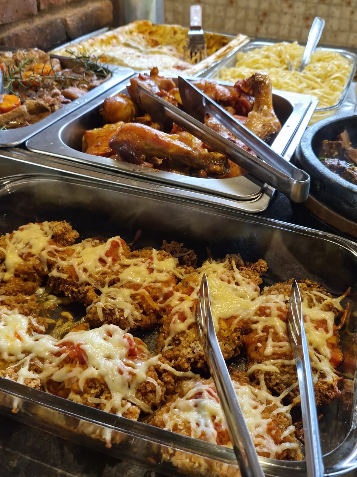 Buffet do restaurante com filé à parmegiana, frango assado e massas nas cubas