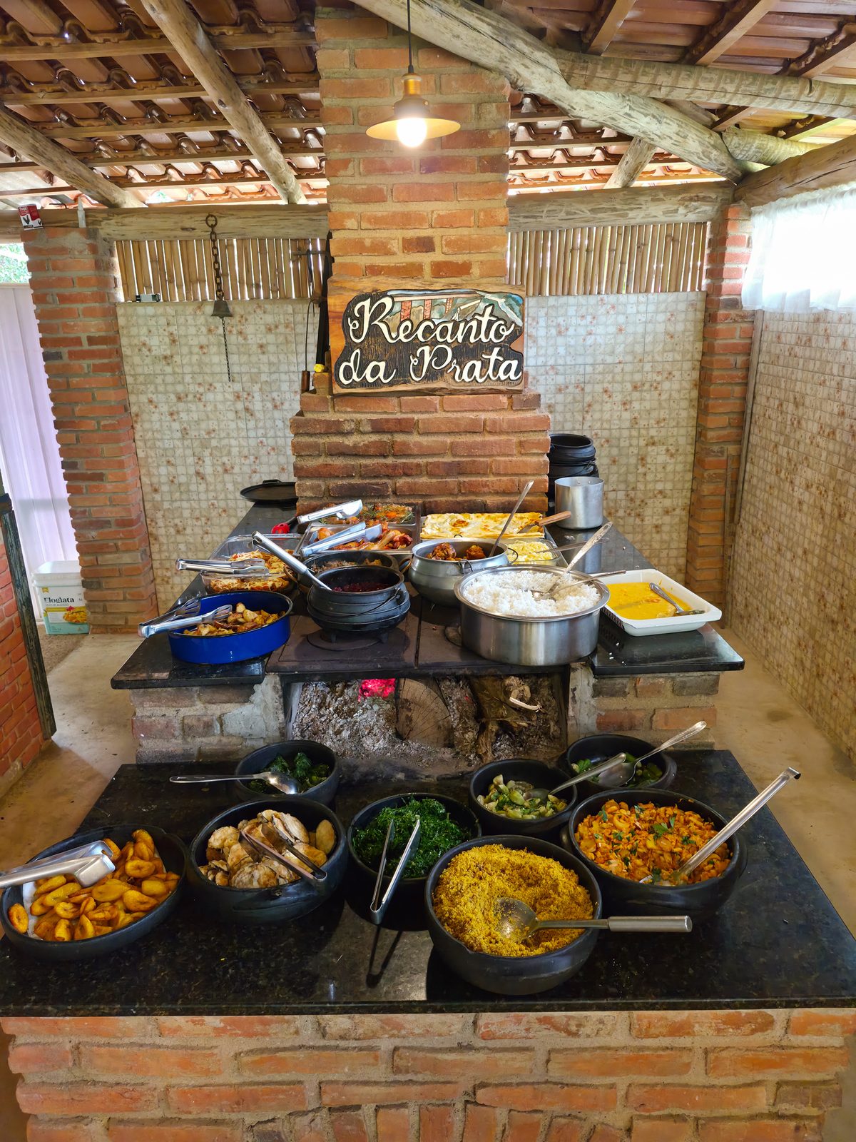 Fogão a lenha do restaurante com panelas e travessas do almoço servidas sobre a bancada