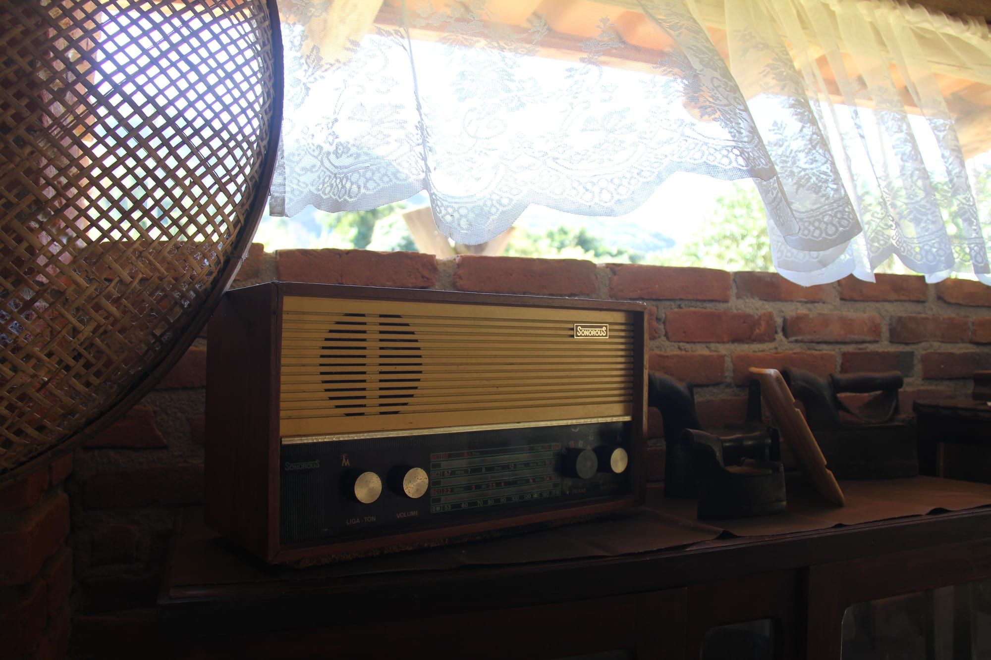 Rádio antigo sobre móvel de madeira junto à janela